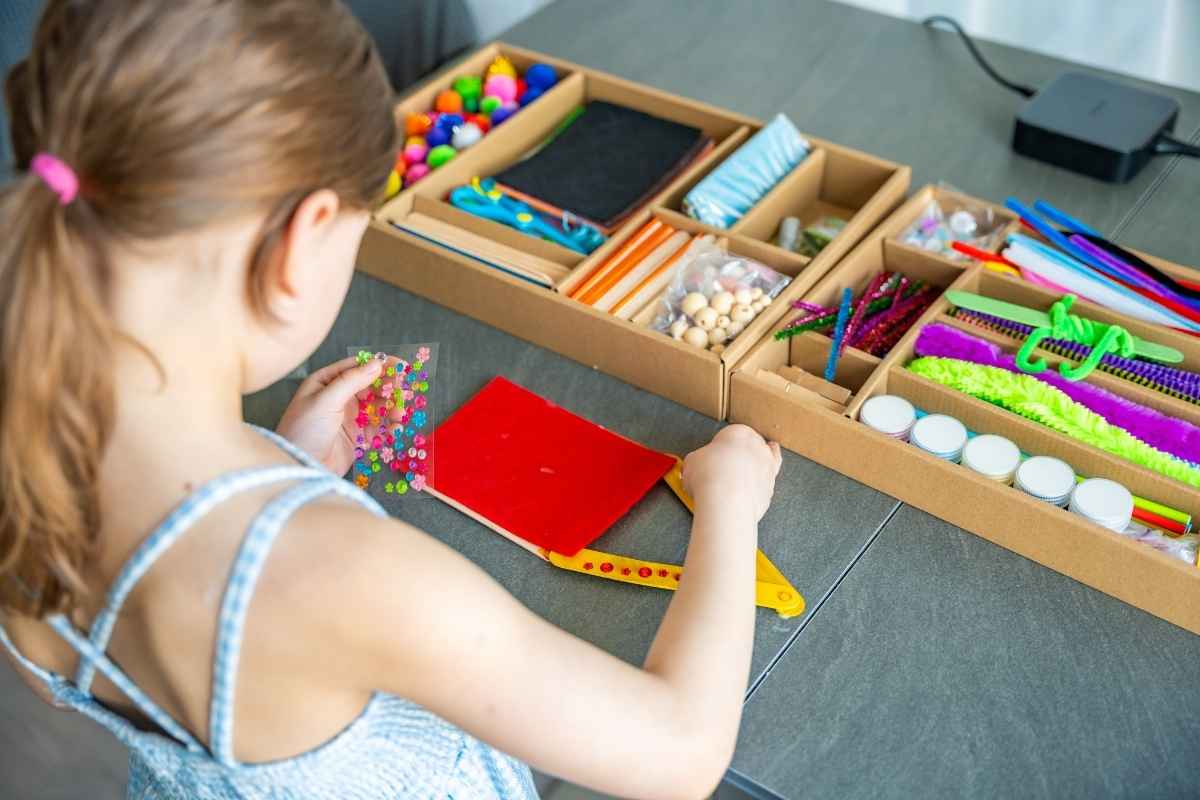 devojčica se igra kod kuće sa stikerima, papirima i flomasterima